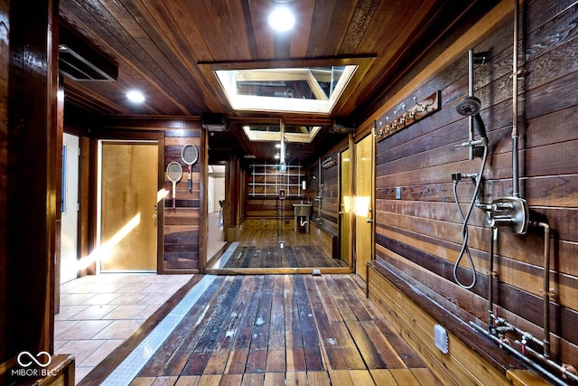 hall featuring a skylight, wood-type flooring, wood ceiling, and wood walls