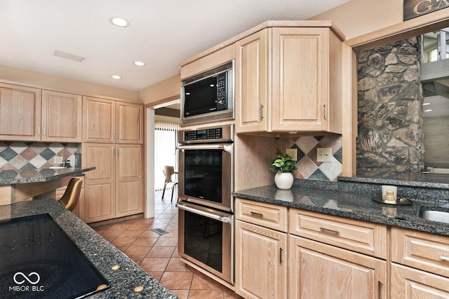 kitchen with light brown cabinets, built in microwave, light tile patterned floors, decorative backsplash, and black electric cooktop