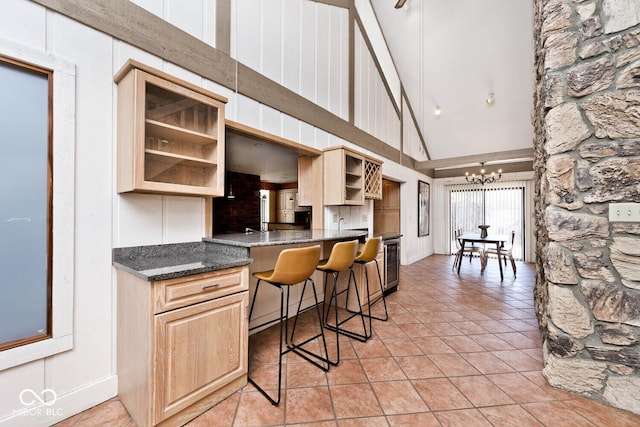 kitchen featuring light tile patterned floors, beverage cooler, an inviting chandelier, open shelves, and a towering ceiling