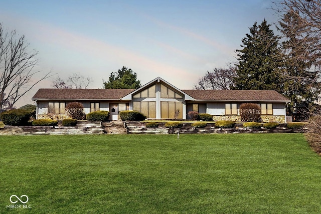 english style home featuring stone siding and a front lawn