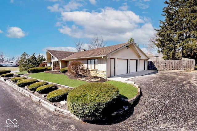 ranch-style house featuring aphalt driveway, an attached garage, and fence