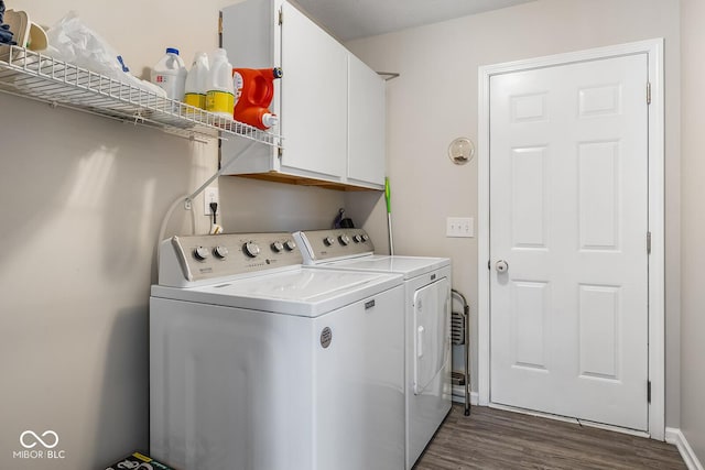 laundry room with washing machine and clothes dryer, dark wood-style floors, and cabinet space