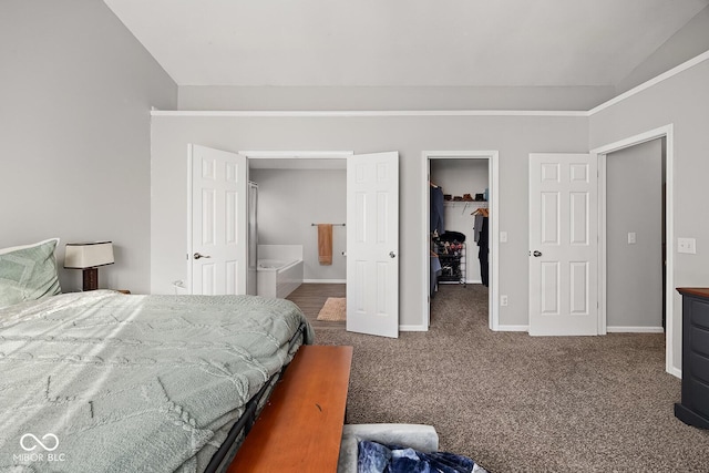 carpeted bedroom with a walk in closet, lofted ceiling, baseboards, and a closet