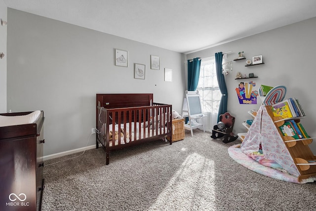 bedroom with a nursery area, baseboards, and carpet floors