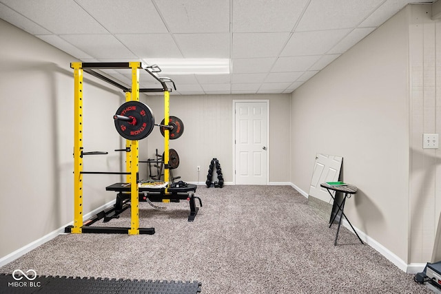 exercise room featuring a drop ceiling, carpet flooring, and baseboards