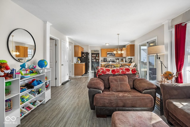 living area with a chandelier, a textured ceiling, and dark wood-type flooring