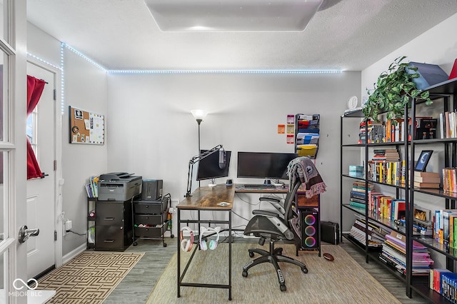 office featuring a textured ceiling, baseboards, and wood finished floors