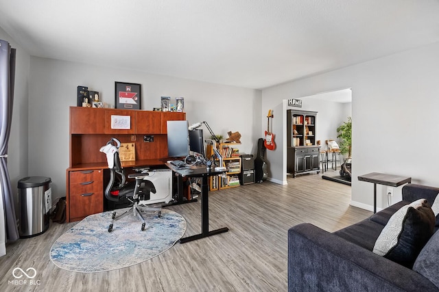 home office with baseboards and light wood finished floors