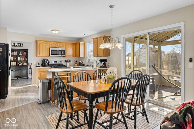 dining space featuring an inviting chandelier, light wood-style flooring, and visible vents