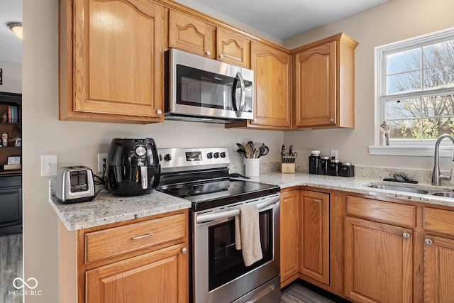 kitchen with light stone counters, stainless steel appliances, and a sink