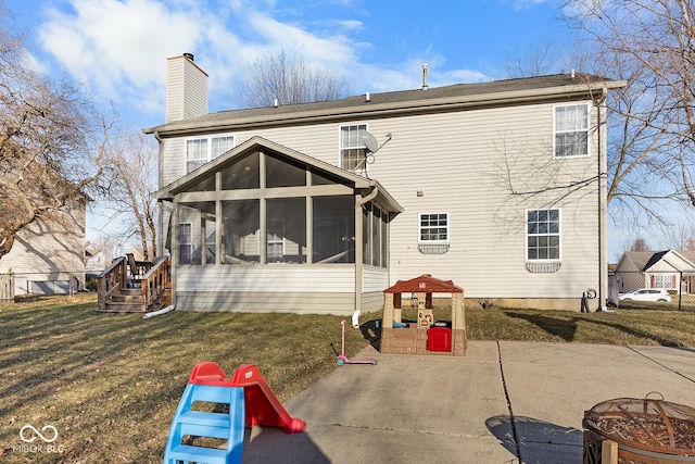 back of house featuring a patio area, a lawn, a chimney, and a sunroom