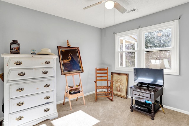 living area featuring ceiling fan, light colored carpet, visible vents, and baseboards