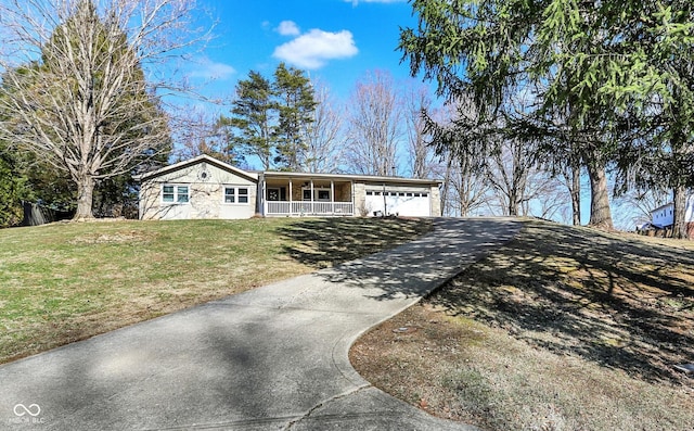 ranch-style home featuring driveway, an attached garage, covered porch, and a front lawn