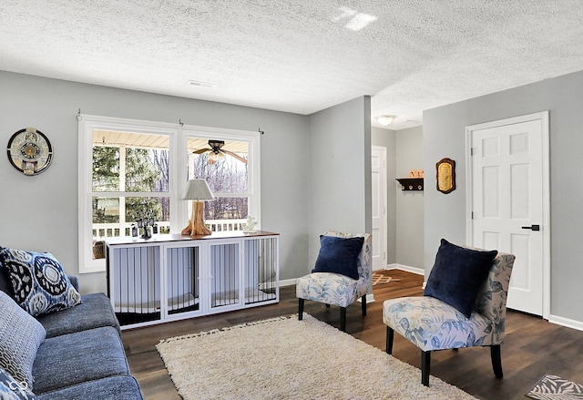 living area featuring a textured ceiling, dark wood-type flooring, and baseboards