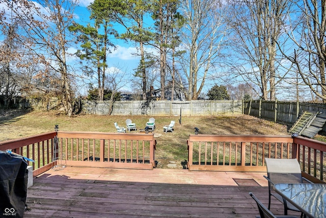 wooden deck featuring a lawn, a grill, and a fenced backyard