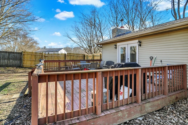 wooden terrace featuring french doors and a fenced backyard