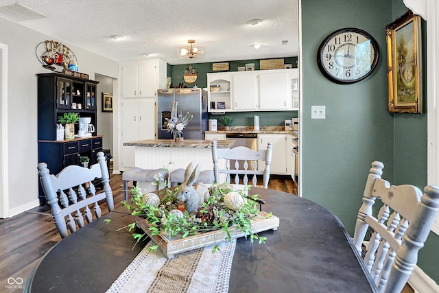 dining area with visible vents, baseboards, a textured ceiling, and dark wood-style flooring