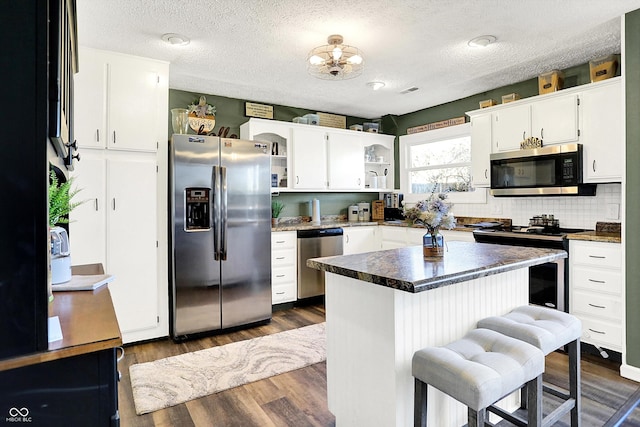 kitchen featuring dark countertops, white cabinets, dark wood-type flooring, and stainless steel appliances