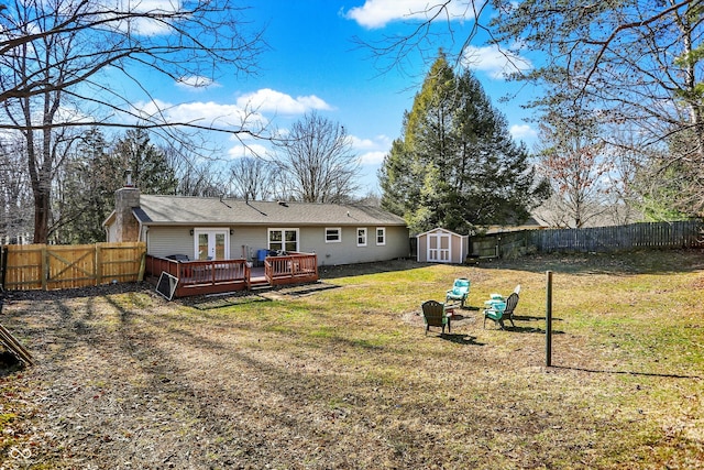 back of property with a storage unit, french doors, a fenced backyard, and a wooden deck