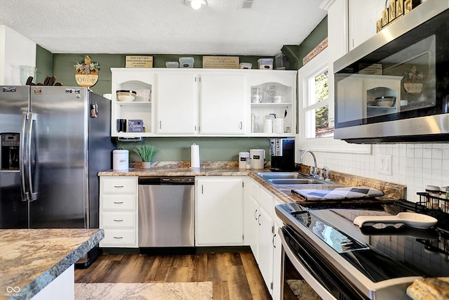 kitchen with open shelves, stainless steel appliances, dark wood-style floors, white cabinetry, and a sink