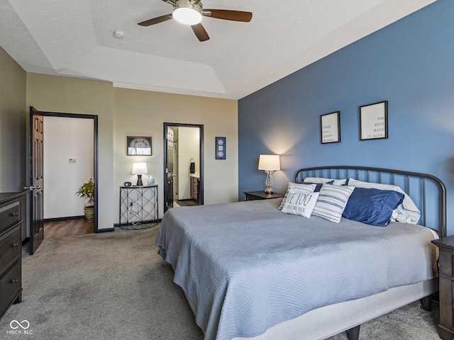 carpeted bedroom featuring ceiling fan, a raised ceiling, baseboards, and a textured ceiling