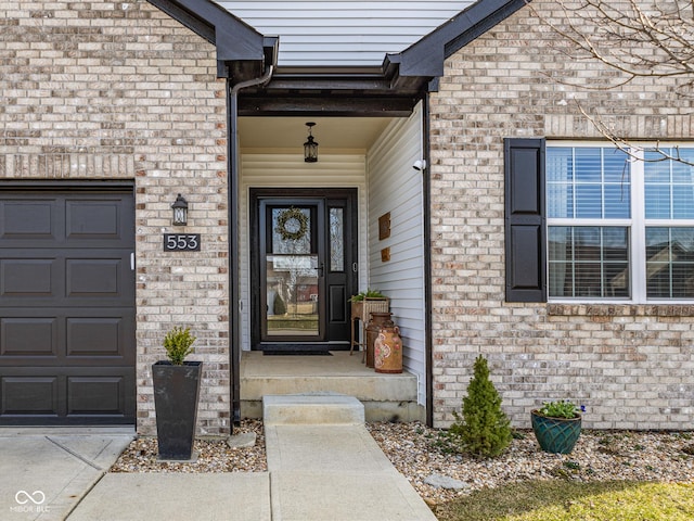 entrance to property featuring a garage and brick siding