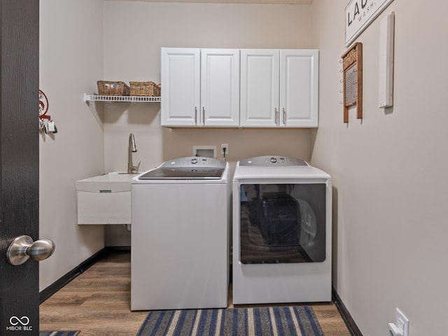 laundry room featuring cabinet space, washing machine and dryer, baseboards, and wood finished floors