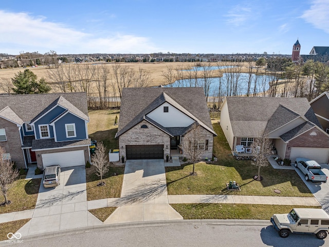 view of front of home featuring an attached garage, concrete driveway, a front lawn, and a water view