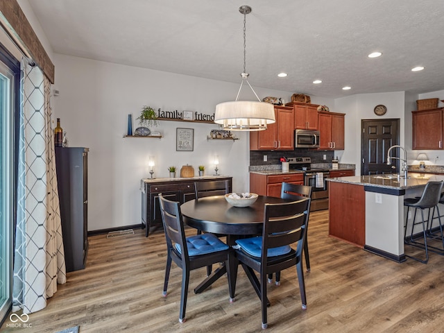 dining area with recessed lighting, light wood-style floors, baseboards, and a textured ceiling