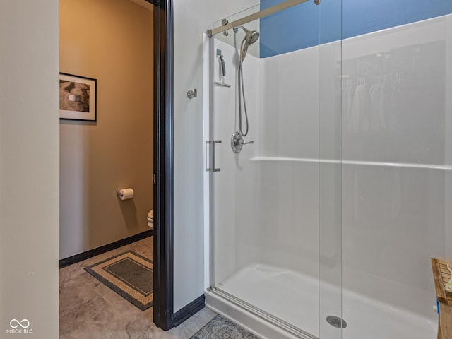 full bathroom featuring baseboards, toilet, and a shower stall