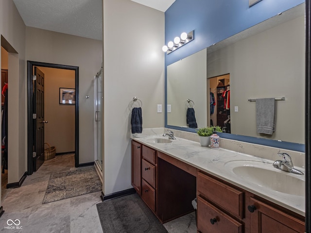 full bath featuring a spacious closet, a shower stall, double vanity, and a sink