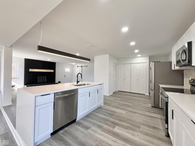 kitchen with light wood-type flooring, open floor plan, appliances with stainless steel finishes, and a sink