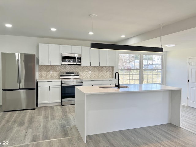 kitchen with light countertops, appliances with stainless steel finishes, light wood-style floors, white cabinets, and a sink