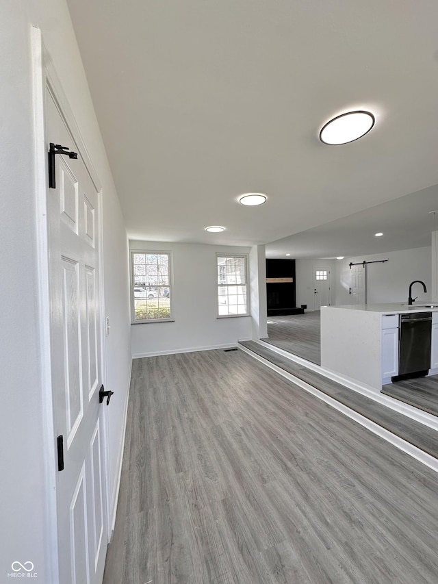 unfurnished living room featuring a sink, baseboards, and light wood-style floors