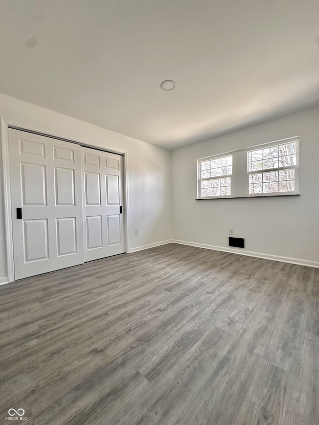 unfurnished bedroom with a closet, baseboards, and wood finished floors