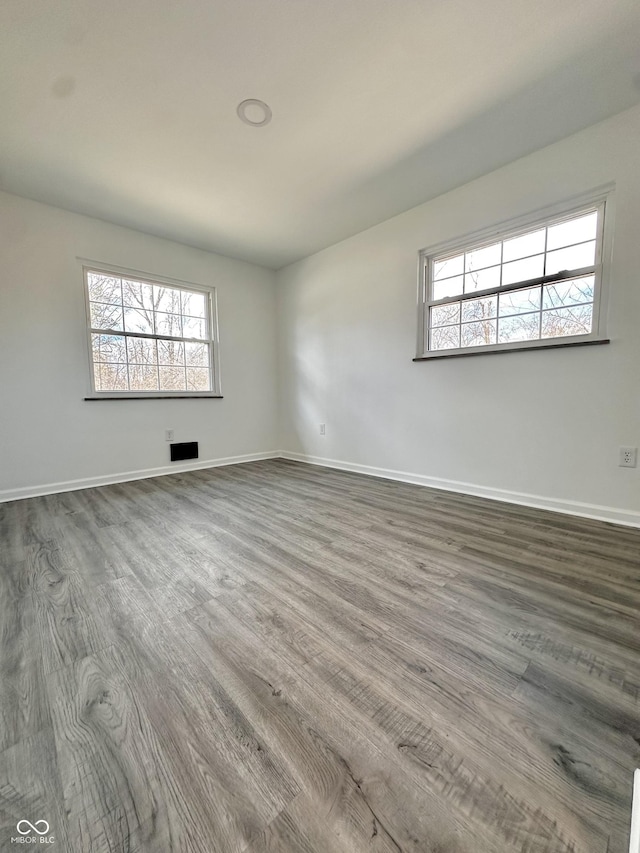 spare room featuring a wealth of natural light, dark wood finished floors, and baseboards