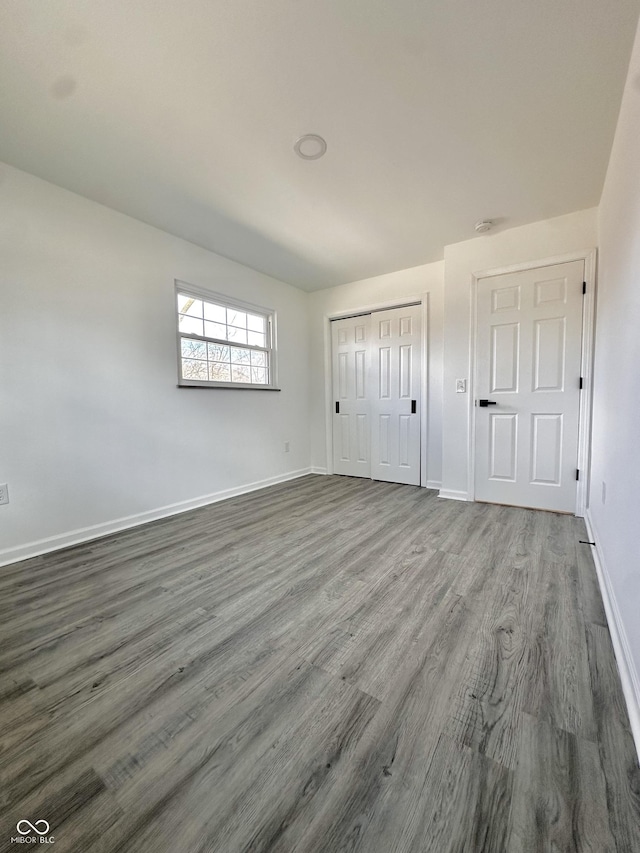 unfurnished bedroom with wood finished floors, baseboards, and a closet