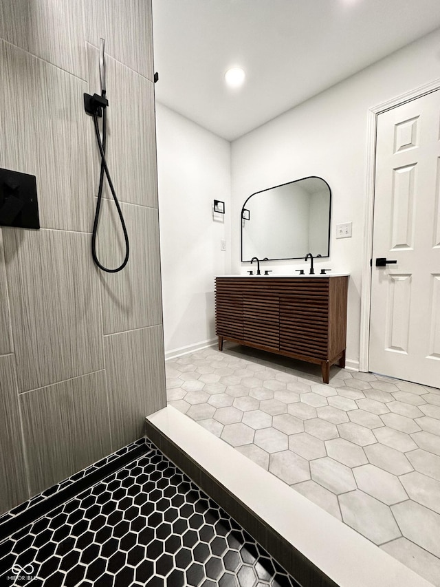 bathroom with recessed lighting, tiled shower, tile patterned flooring, double vanity, and baseboards