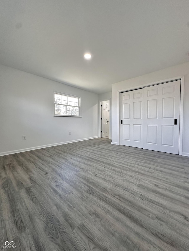 unfurnished bedroom with recessed lighting, a closet, baseboards, and dark wood finished floors