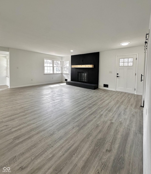 unfurnished living room featuring a fireplace, wood finished floors, and baseboards