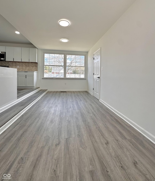 unfurnished living room with baseboards and wood finished floors