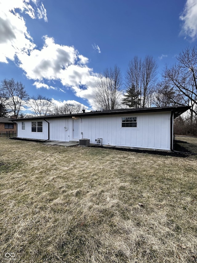 back of house featuring central air condition unit and a lawn