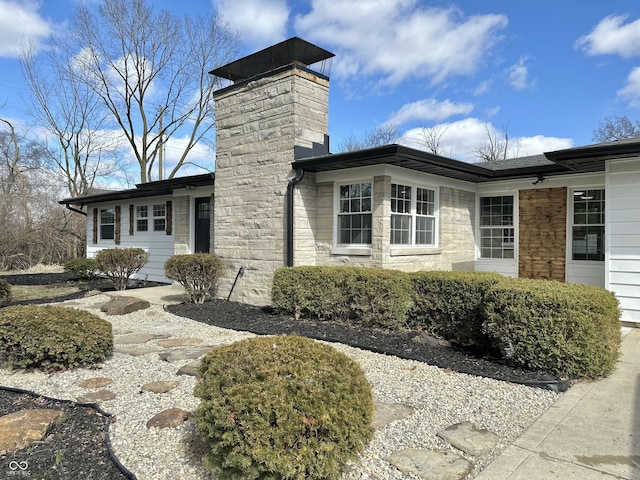 view of home's exterior with stone siding and a chimney