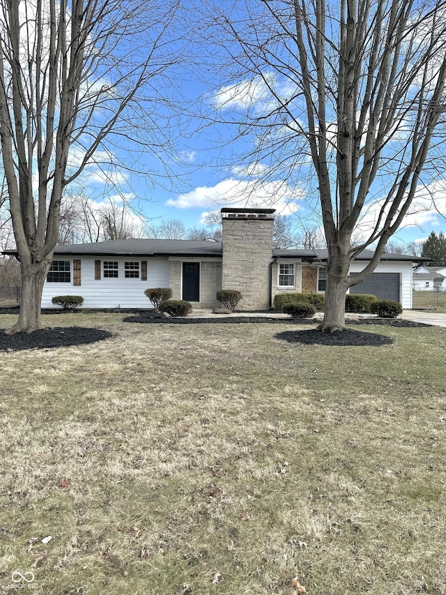 view of front of property featuring a chimney, a garage, and a front yard