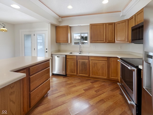 kitchen featuring light wood finished floors, brown cabinets, stainless steel appliances, and a sink