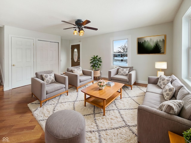 living area with a ceiling fan, baseboards, and wood finished floors