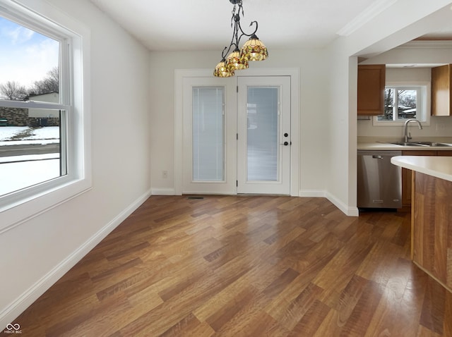 unfurnished dining area with a sink, a notable chandelier, baseboards, and dark wood-type flooring