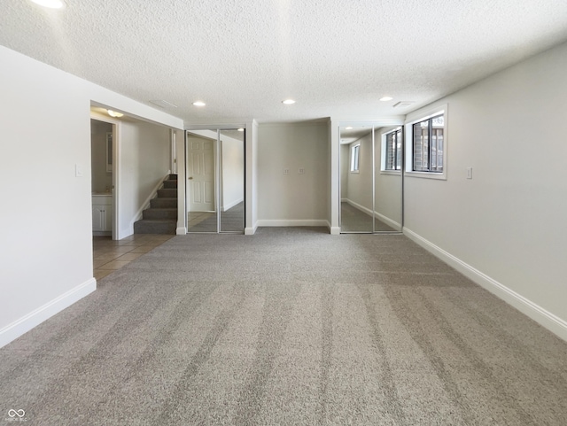 basement with baseboards, recessed lighting, stairs, a textured ceiling, and carpet flooring