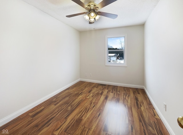 empty room featuring ceiling fan, visible vents, baseboards, and wood finished floors