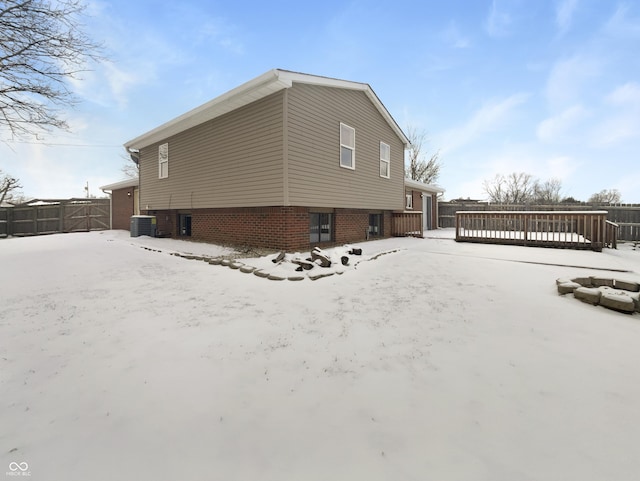 view of snowy exterior featuring cooling unit, a wooden deck, and fence